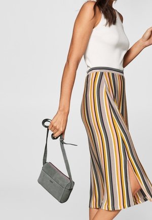 Gonna midi a righe nei toni del giallo, rosa, grigio e marrone; presenta uno spacco laterale. Abbinata a una piccola borsa a spalla grigia con tracolla.