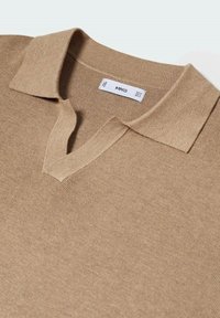 Písečný pletený polo tričko s výstřihem do V a krátkým límcem. Hladká textura, minimální detaily prošití, štítek viditelný uvnitř výstřihu.