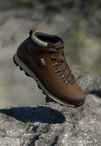 Bota de senderismo marrón con un upper de cuero texturizado y sintético, ojales de metal y suela resistente para tracción. Sin marcas de marca visibles.