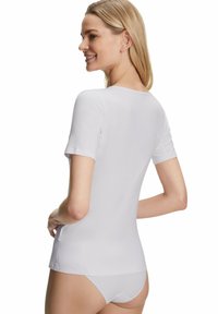 Camicetta bianca a maniche corte con scollatura rotonda, tessuto liscio e design aderente, abbinata a biancheria intima coordinata, che mostra uno stile minimalista.