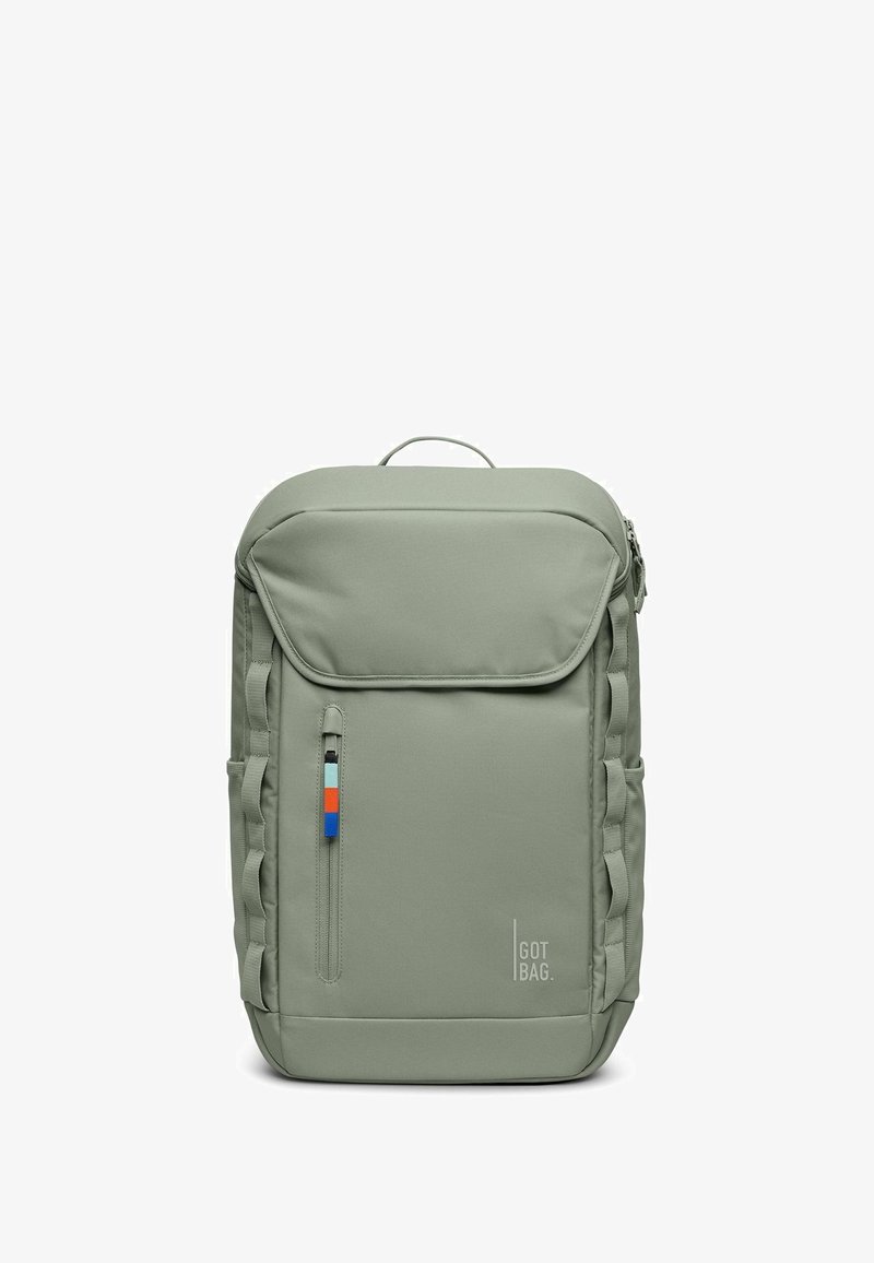 Mochila de tela verde con solapa superior, bolsillo frontal, detalles en cremallera azul, naranja y blanca, y acentos en las correas laterales. Cuenta con un asa en la parte superior.