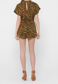 Romper w kwiatowym wzorze, z krótkimi rękawami, elastyczną talią i zapięciem w kształcie łezki na plecach; charakteryzuje się ziemistymi odcieniami zieleni, żółci i rdzy. Połączony z brązowymi szpilkami.