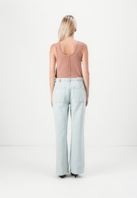 Lichtroze geribd tanktop met een ronde hals, gecombineerd met high-waisted lichtblauwe wijde spijkerbroeken met achterzakken.