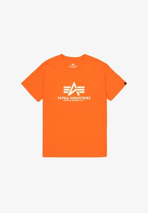 Narančasta pamučna majica s bijelim logotipom s apstraktnim dizajnom i natpisom "ALPHA INDUSTRIES" centriranom sprijeda.