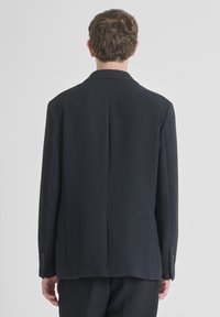 Mornarica sako od teksturiranog materijala, s odrezanim reverima, jednim prorezom straga i dugmadima na rukavima. Prilagođen kroj s čistim linijama.