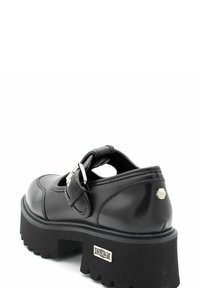 Zwarte leren schoen met een ronde neus, uitgesneden ontwerp, verstelbare band en chunky zwarte rubberen zool met een geribbelde textuur.