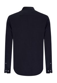 Marineblå langærmet skjorte med knaplukning på kraven, tekstureret stof, buet skørt og manchetter med knapper. Bagsiden er uden mønstre eller detaljer.