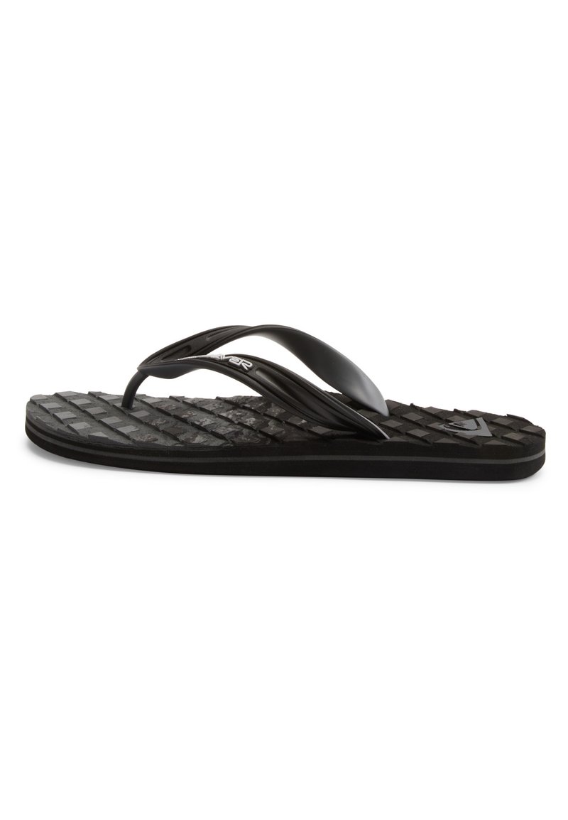 Musta flip-flop, jossa on texturoitu kumipohja, joustavat hihnat ja lievä kaarituki. Pohjassa on selkeä kuviointi.