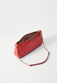 Sac à main en cuir rouge avec des accents en chaîne dorée, fermeture éclair et texture lisse. Comprend un intérieur marron et une étiquette de logo à l'intérieur.