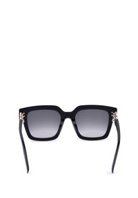 Lunettes de soleil carrées noires surdimensionnées avec verres à dégradé foncé et branches noires brillantes vues de face sur fond blanc.