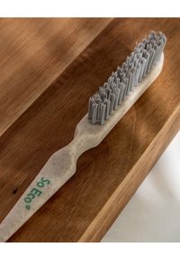 Spazzolino ecologico con manico beige e testurizzato e setole grigie. Il nome del marchio "So Eco" è visibile sul manico.