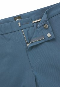 Blue trousers with a textured fabric. Features a zip fly, button closure, and a brand tag labeled "BOSS." Clean design with subtle stitching.