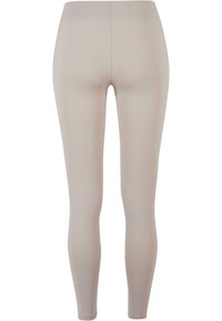 Leggings beige en tissu extensible avec une texture lisse. Le design présente une taille haute et une silhouette ajustée. Sans coutures visibles.
