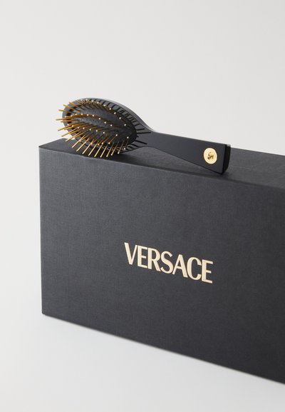 Μαύρη βούρτσα μαλλιών με χρυσά τσιμπιδάκια, οβάλ σχεδίαση, ματ λαβή, τοποθετημένη σε μαύρο κουτί με χρυσό λογότυπο "VERSACE".