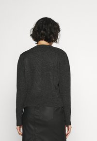 Ciemnoszary sweter z długimi rękawami i zaokrąglonym dekoltem, o lekko krótkim fasonie i teksturowanym wykończeniu.