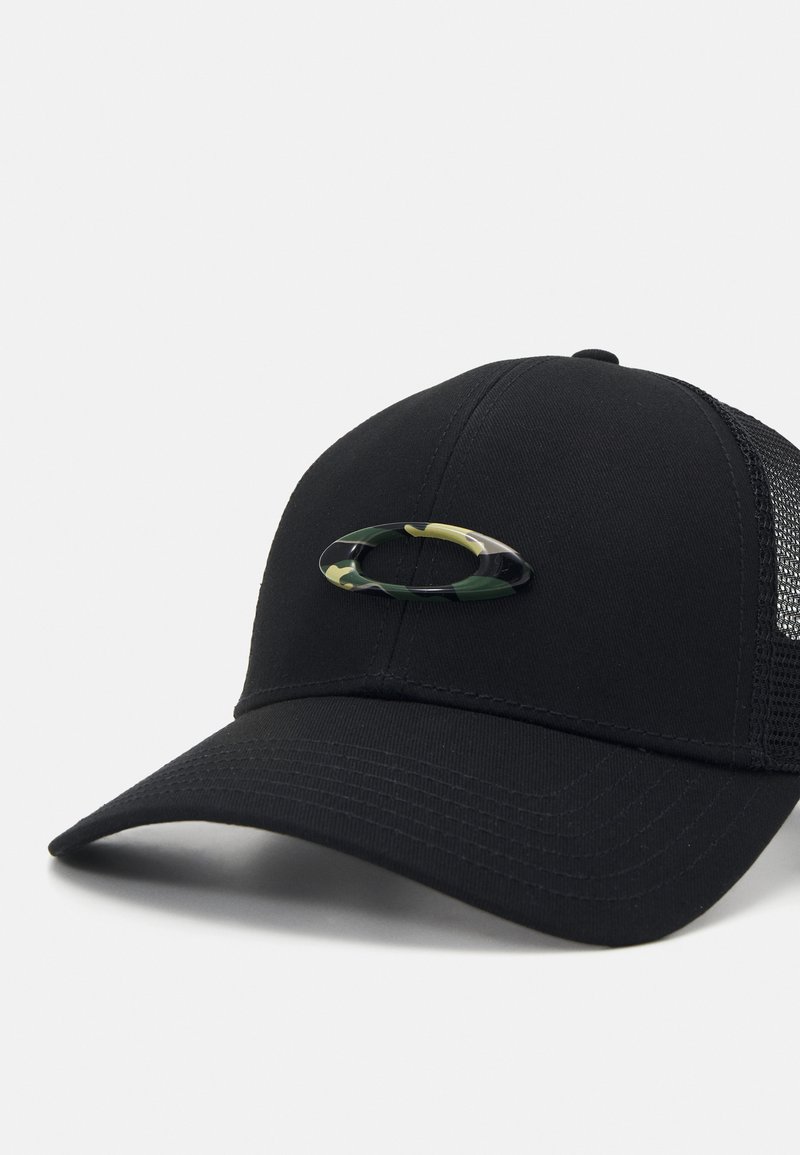 Svart keps med en strukturerad front, nät-sidor och en svängd skärm. Har en grön och gul kamouflage oval logotyp på framsidan.