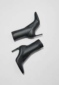 Svarta läderankelboots med spetsiga tår, stilettklackar och eleganta sidokut. Slät textur och minimalistisk design.