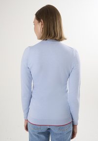 Maglione azzurro chiaro a maniche lunghe con scollatura rotonda e dettaglio rosso all'orlo. Texture lavorata a maglia liscia con silhouette aderente.