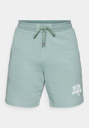 Șorturi din bumbac verde deschis, cu talie elastică și șnur. Include un logo alb "PUMA sports club" în colțul stâng jos. Textură netedă.