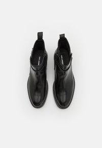 Black leather ankle boots with a smooth finish, round toes, and decorative zippers on each side. Stitched detailing along the soles.