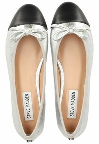 Ballerines métalliques argentées avec un bout en cuir noir, un détail en nœud à l'avant et une semelle intérieure lisse de couleur claire.