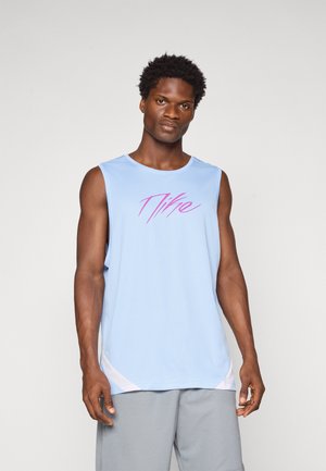 Camiseta atlética sin mangas de color azul claro con una tela texturizada, que presenta un diseño gráfico rosa en el pecho. Shorts grises llevados por debajo.