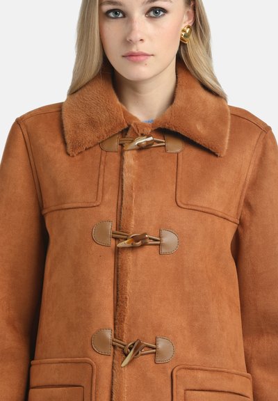 Cappotto in suede marrone con colletto in pelliccia sintetica, chiusure a toggle e tasche a toppa; presenta una texture morbida e una forma sartoriale.