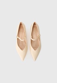 Pair of beige pointed-toe Mary Jane shoes with gold buckle straps, displayed side by side on a white background.