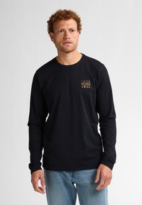 Schwarzes Langarm-T-Shirt aus Baumwolle mit einem kleinen goldenen Grafiklogo auf der linken Brustseite. Lässige Passform mit Rundhalsausschnitt.