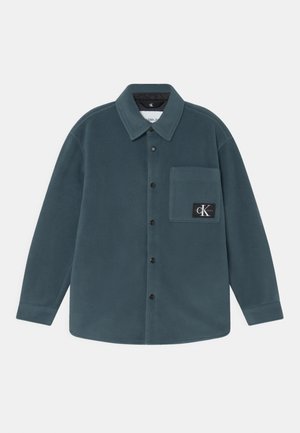 Mørkegrøn bluse i fleece med lange ærmer, spids krave, brystlomme og sort Calvin Klein Jeans logo-patch på lommen.