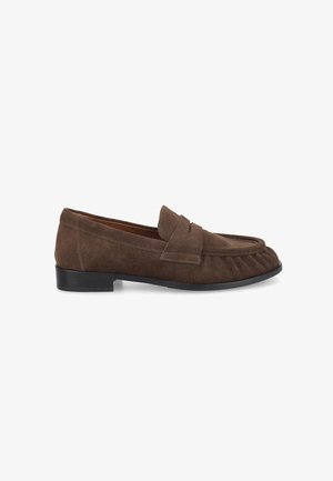 Mocassin en daim marron avec un petit talon noir, un bout arrondi et un détail de bride cousue sur le dessus.