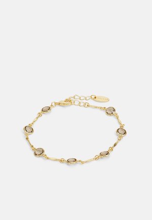 Bracelet chaîne en or avec des pierres ovales en quartz fumé et un fermoir ajustable sur fond blanc.