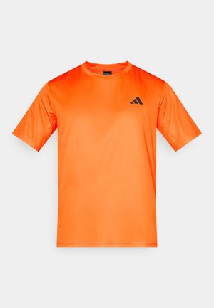 Oranžna športna majica s kratkimi rokavi iz gladkega, vlažnost odvzemajočega blaga. Na levi strani prsnega koša je črn logotip.