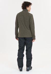 Langærmet, mørkeoliven fleece-top med høj krave, sammen med sorte isolerede bukser og sorte udendørsstøvler. Enkel design, ingen mønstre.