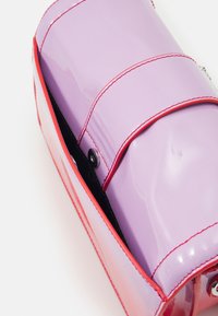 Zastrzeżona torebka o połyskującym wykończeniu, z lawendowym korpusem i kontrastowymi czerwonymi akcentami, zamykana na zatrzask i ozdobne przeszycia.