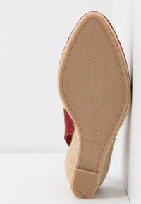 Dessus rouge en tissu texturé avec un talon en jute tissé. La semelle en caoutchouc présente un motif de crampons. Taille 37 indiquée au dos.
