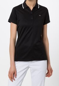 Černé polokošile z hladké látky s klasickým límečkem s bílými akcenty, zapínáním na knoflíky a malým logem na hrudi.