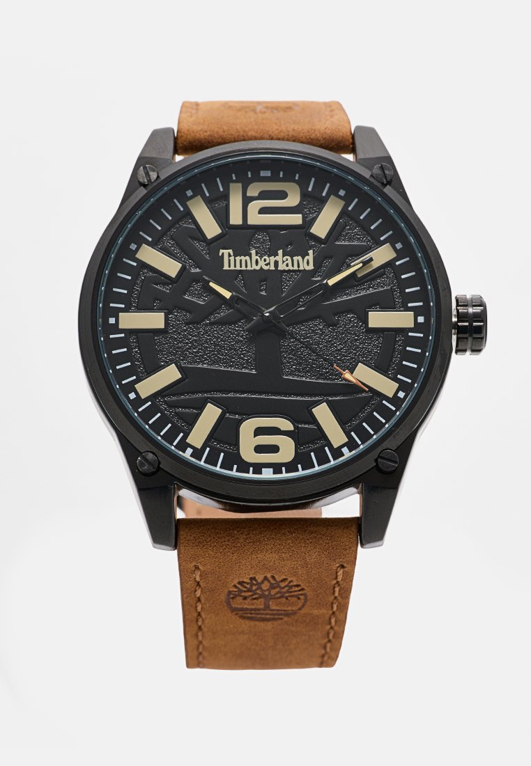 Reloj analógico negro con un dial negro texturizado, grandes números beige y una correa de cuero marrón con el logo de Timberland.