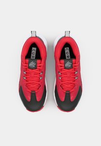 Red athletic shoes with black accents, mesh and suede material, six eyelets, padded tongue, and white rubber sole. Logo displayed on tongue.
