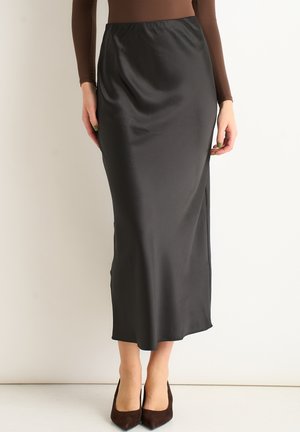 Black satin midi skirt with a smooth texture, featuring a fitted waistband and a side slit. Paired with brown high-heeled shoes.