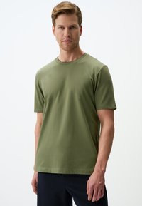 Oliwkowa koszulka z krótkim rękawem z miękkiego materiału, okrągły dekolt, z prostym wzorem bez widocznych motywów ani ozdób.