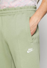 Ljusgröna sweatpants i mjukt tyg, med sidofickor och en vit Nike-logotyp på vänster lår. Elastiskt midjeband ingår.