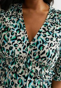 Leopard print dress featuring a deep V-neck, short sleeves, ruffled waist, and a blend of black, teal, and light green colors on a white base.