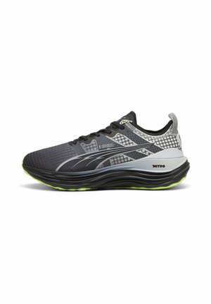 Scarpe da ginnastica nere e grigie con una tomaia in rete testurizzata, dettagli riflettenti e una suola verde. Design leggero con un'intermedia ammortizzata.