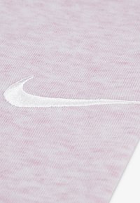 Nike pink fabric with a textured pattern, featuring a white embroidered logo. The material appears soft and slightly heathered.