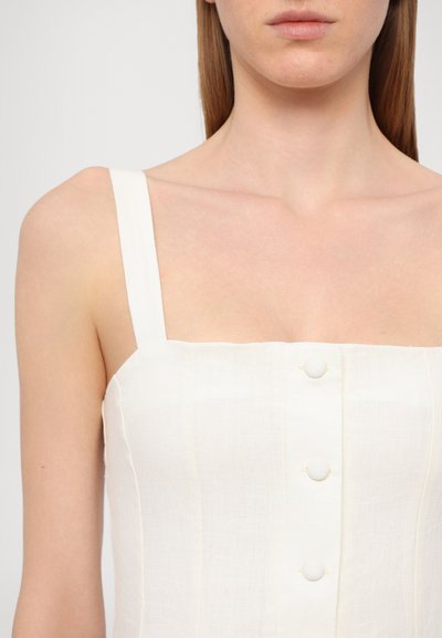 Vestido de lino blanco con escote cuadrado, tirantes finos y cierre frontal con botones. Presenta costuras verticales y una textura sutil.