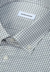 Chemise blanche à petit motif à carreaux noirs avec une étiquette indiquant "seidensticker" à l'intérieur du col.