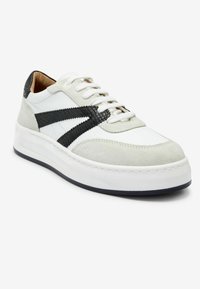 Sneaker bianca e grigia con una striscia nera testurizzata, materiali in suede e pelle, punta rotonda e suola bianca spessa.