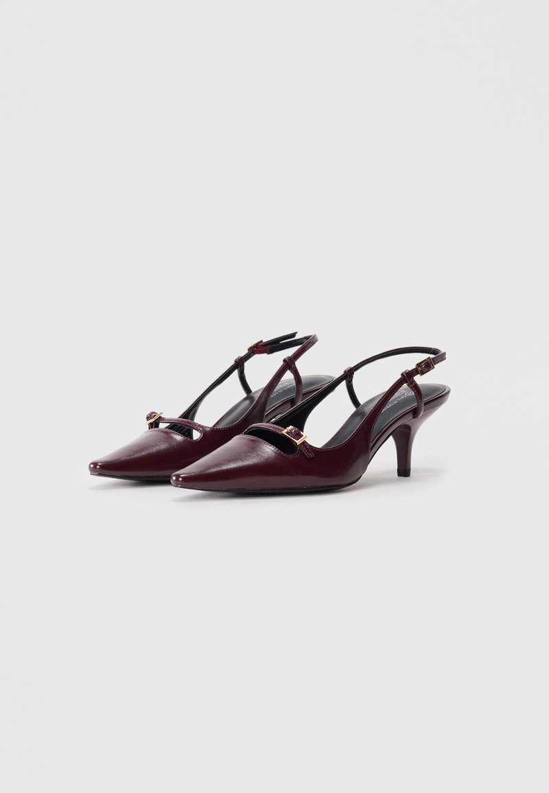 Escarpins burgundy en cuir à brides arrière avec bouts pointus, détails découpés et accents en métal doré. Ils disposent d'un talon bas et de brides ajustables.
