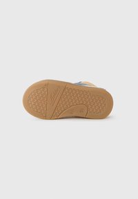 Semelle de chaussure en caoutchouc marron avec un motif texturé, mettant en valeur un accent en tissu bleu. Marquage gravé sur le côté. Finition lisse.